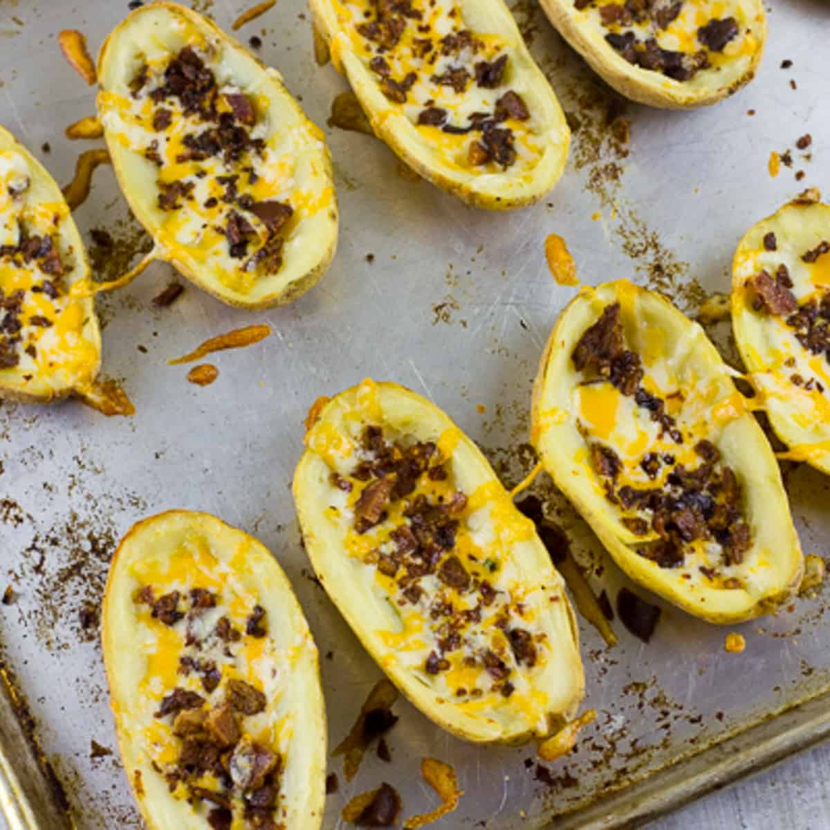 Bacon and cheddar cheese sprinkles on the hollowed out halves of potatoes.