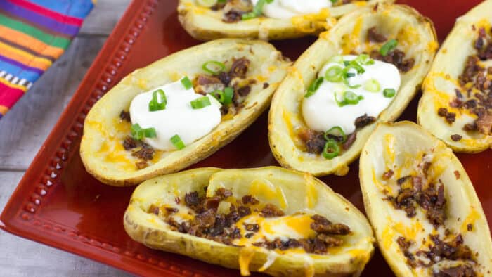 A plate of baked potato skins with a dollop of sour cream.