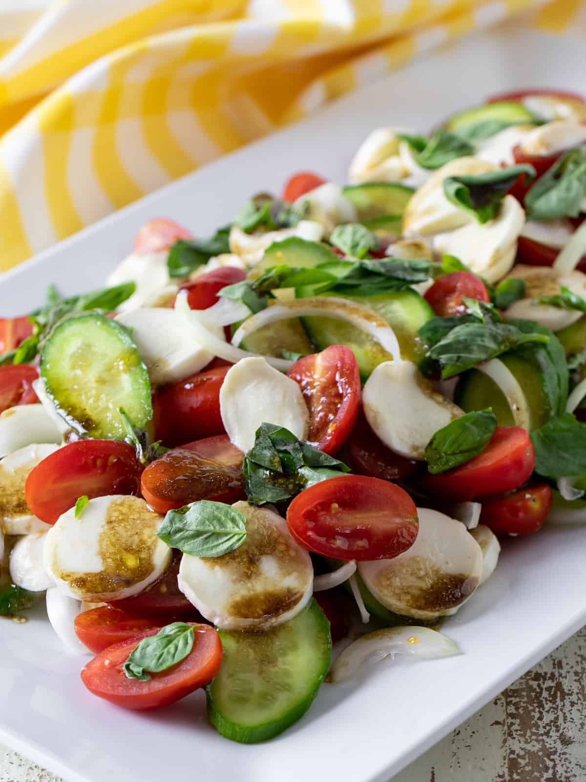 Grape tomatoes, cucumber, tomatoes and fresh mozzarella cheese served in a salad.
