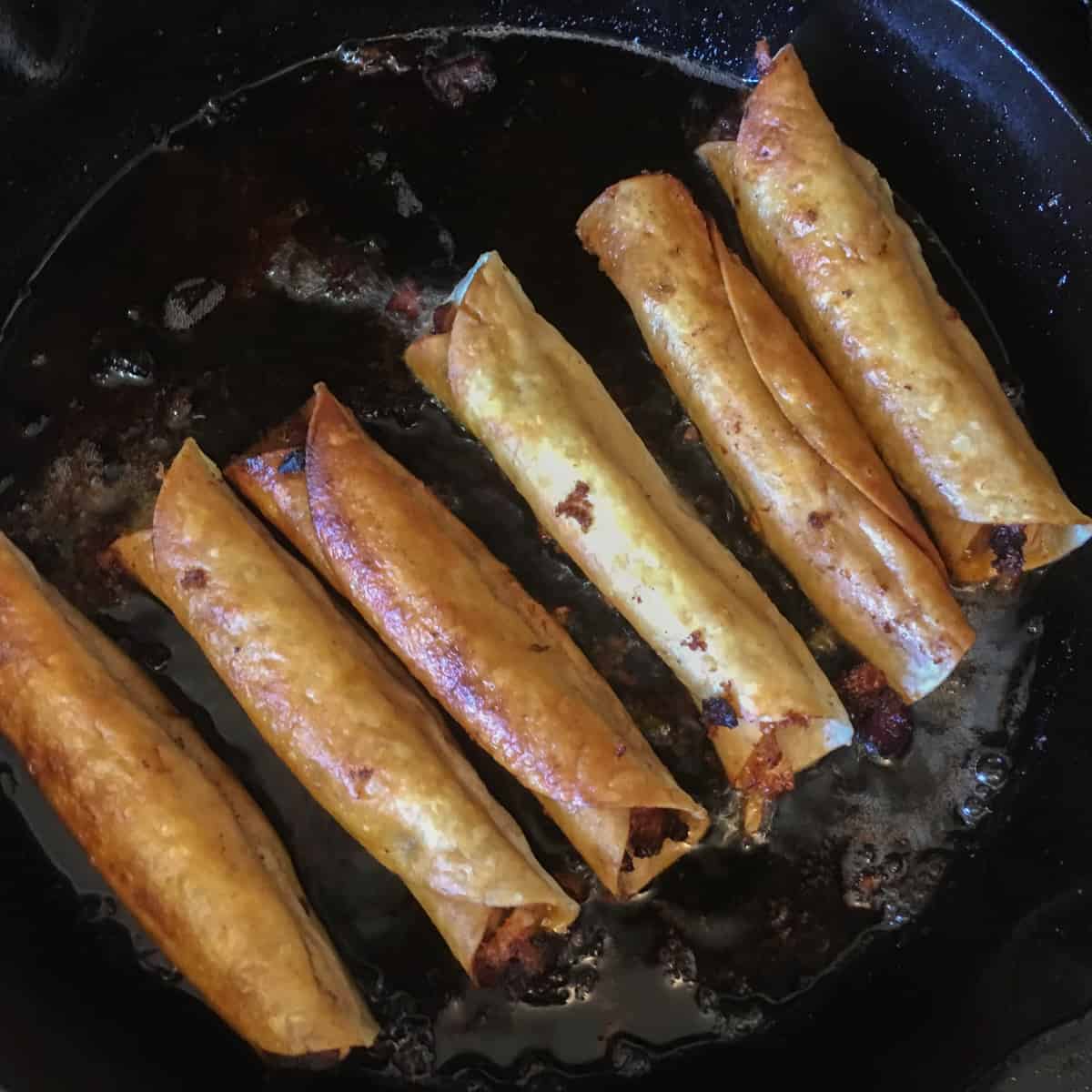 Fried flautas ready to come out of the hot oil.