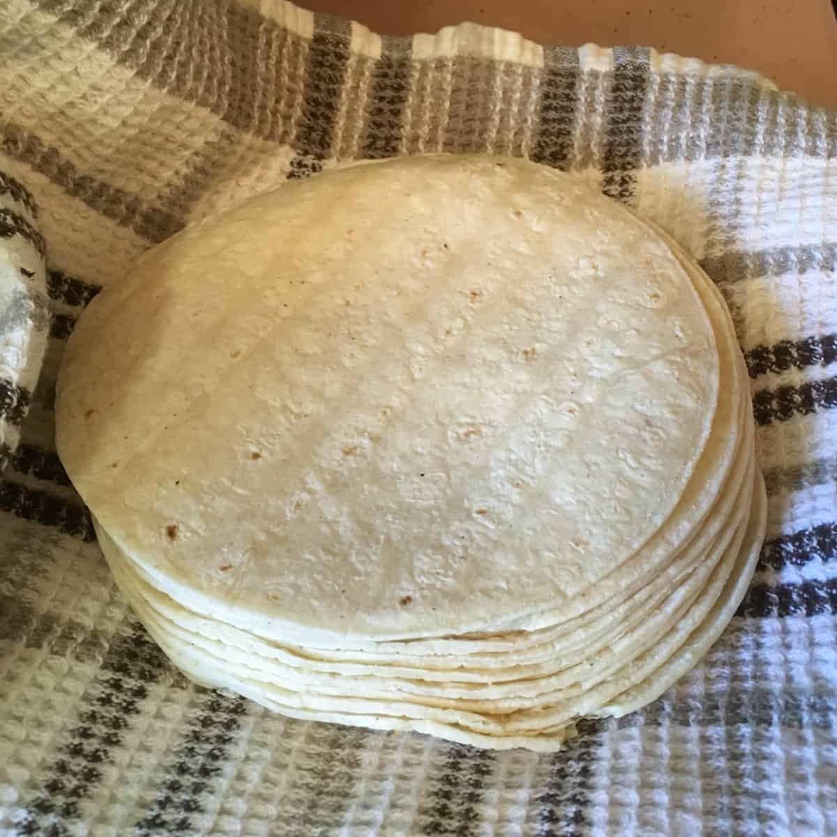 A pile of soft corn tortillas resting on a towel.