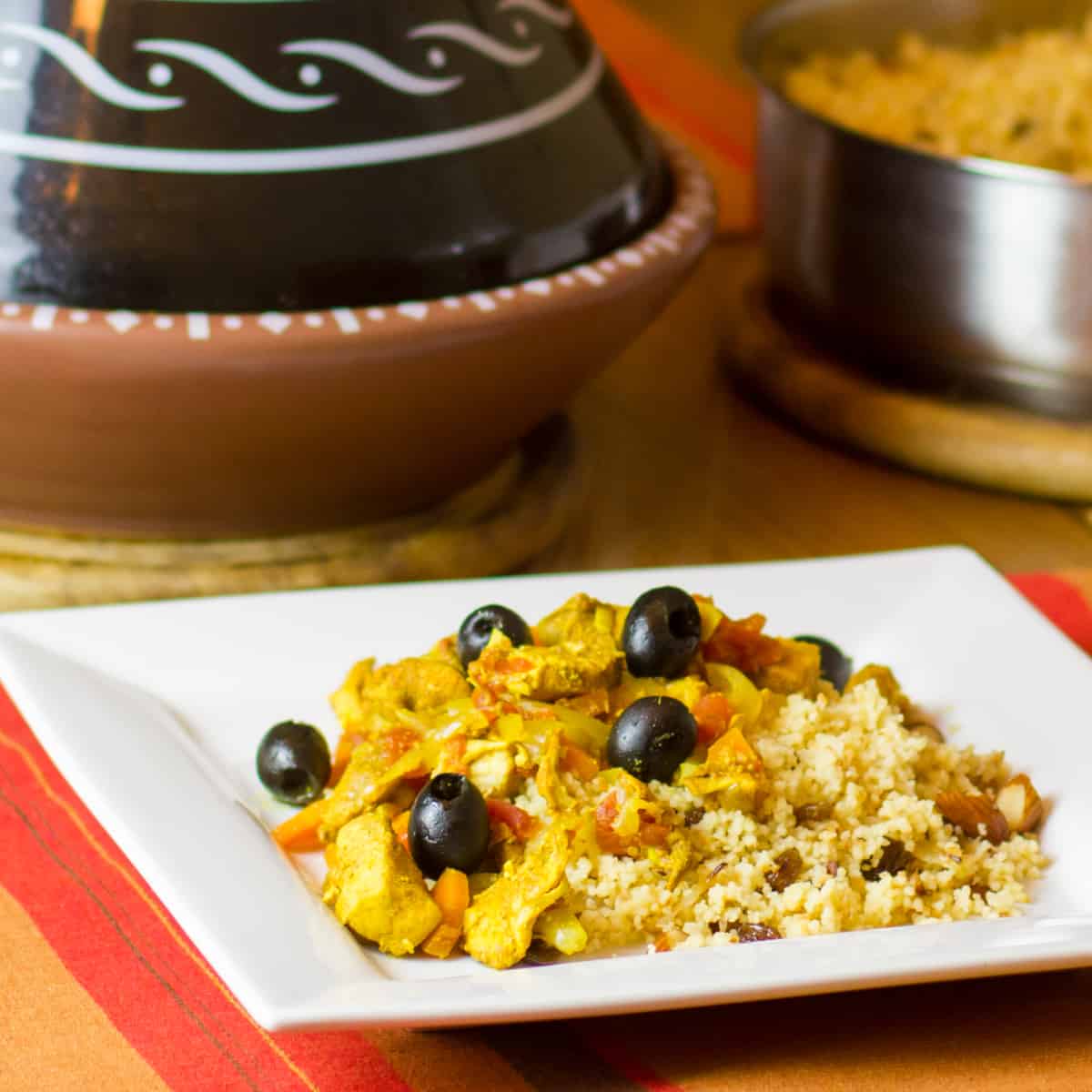 Tagine with chicken and black olives on a plate.