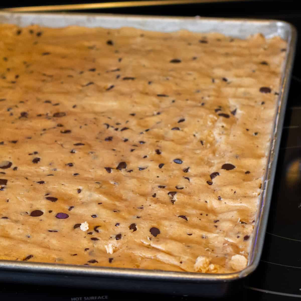 Cookie dough pressing into a baking sheet.