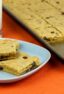 Cookies on a plate next to a glass of milk and baking sheet.