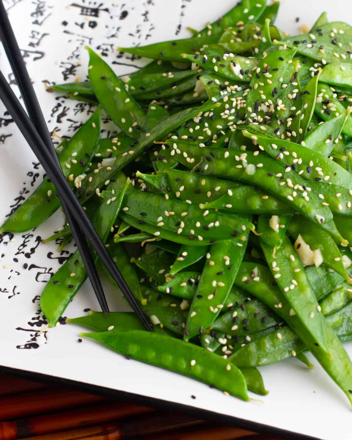 A close up picture of a plate of snow peas garnished with sesame seeds.