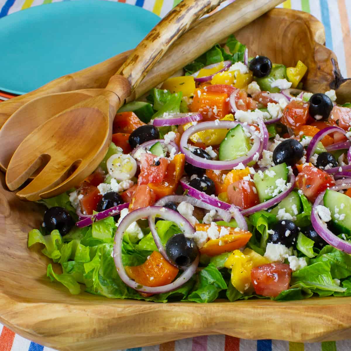 Wooden tongs crossed on top of a salad.