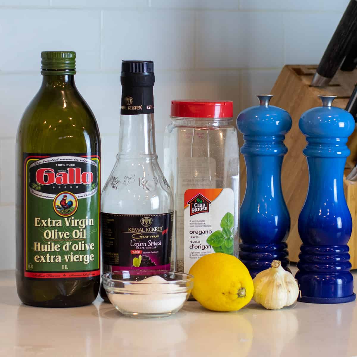 Ingredients for Greek Vinaigrette gathered together on a white kitchen counter.