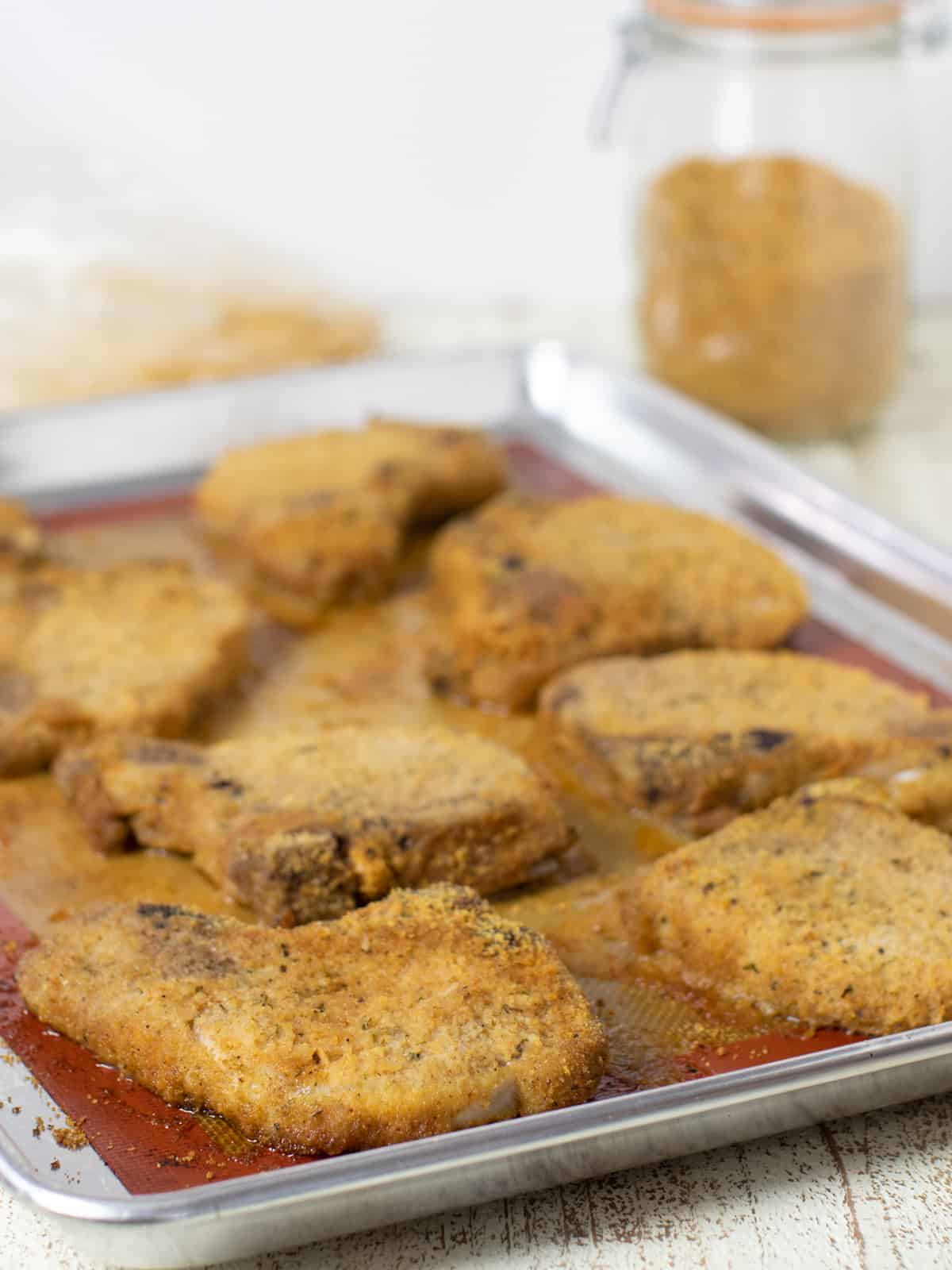 Baked breaded pork chops on a baking sheet.