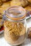 A jar of bread crumb mixture in front of a sheet of baked pork chops.