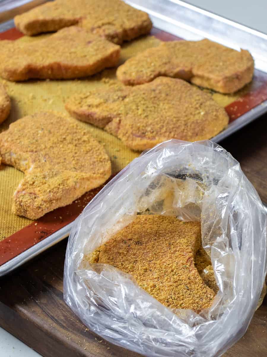 Clear plastic bag open showing a pork chop coated in the seasoned breading.