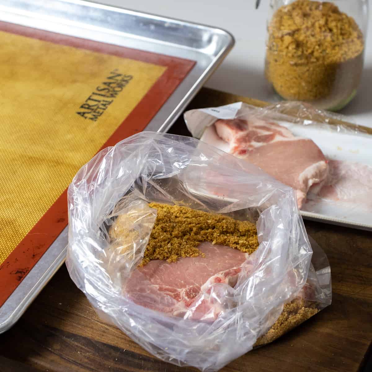 Pork chop and breading mixture added to a clear plastic bag.
