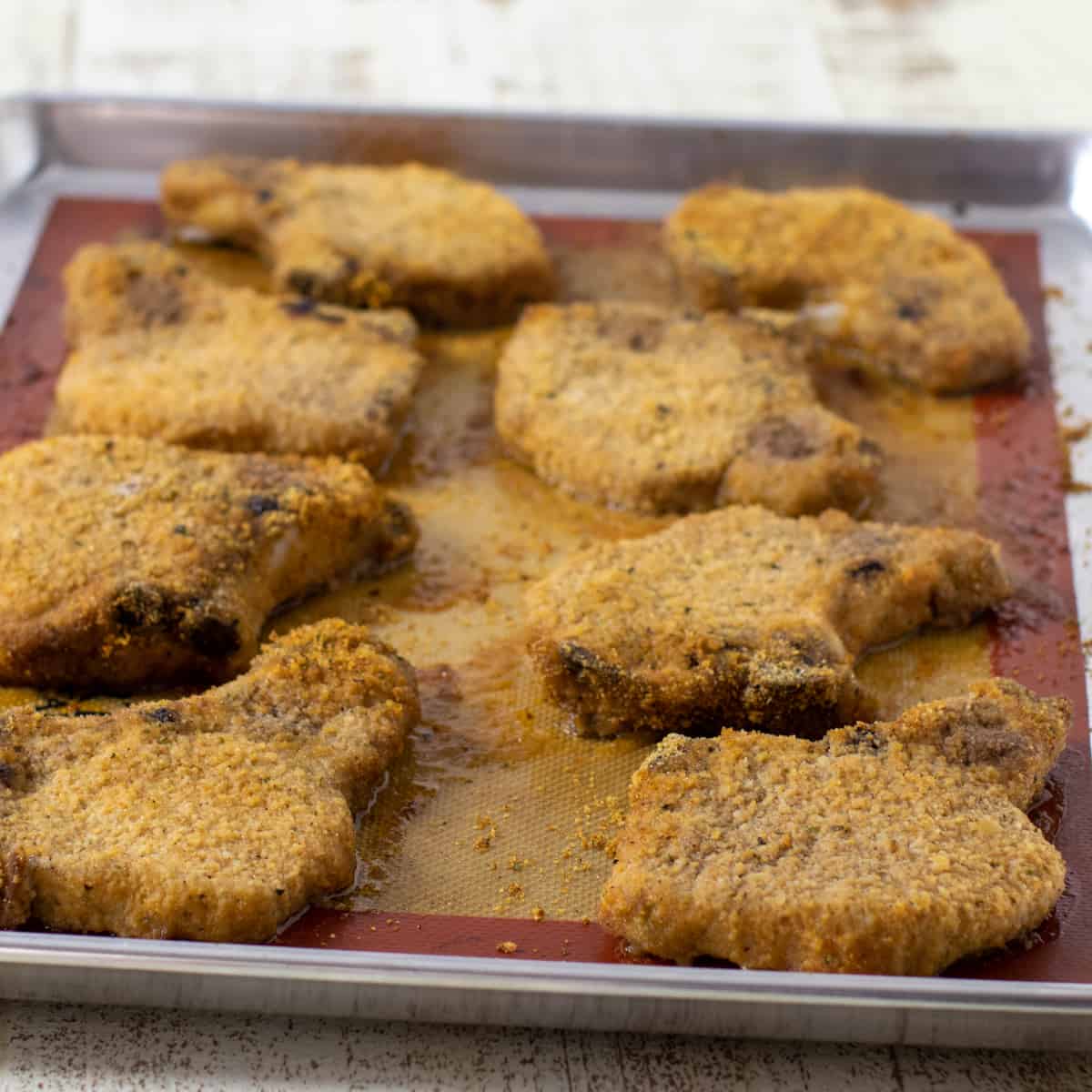 Pork chops on a baking sheet just taken out of the oven.