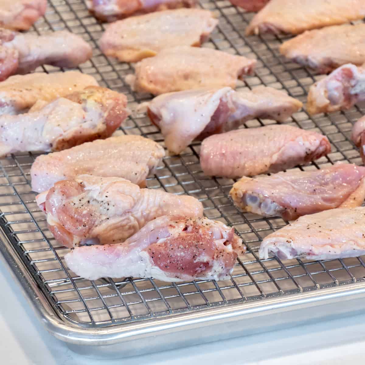 Raw chicken wings on a baking sheet and ready to go in the oven.