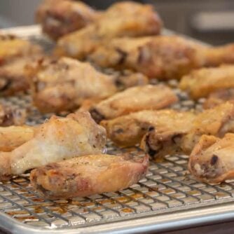 Baked chicken wings on a baking sheet with a rack.