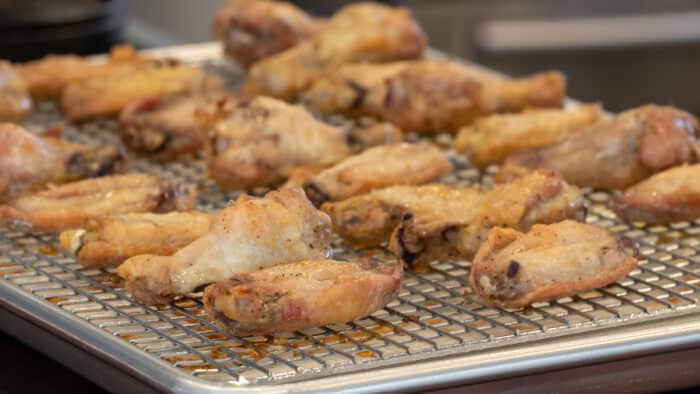 Baked chicken wings on a baking sheet with a rack.