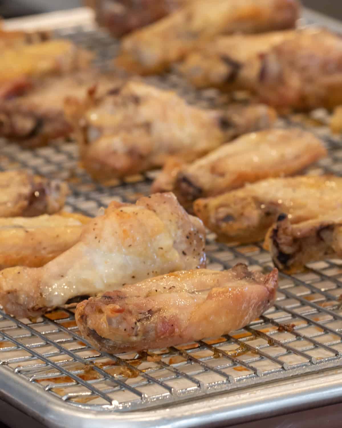 Cooked chicken wings on a baking sheet.