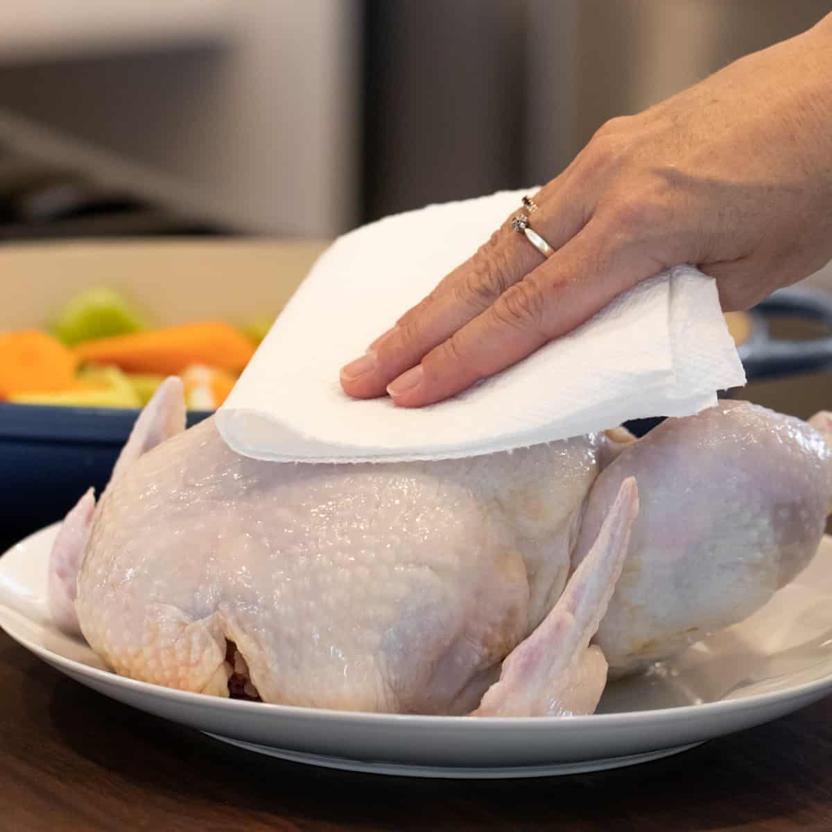 Patting a chicken with a paper towel.