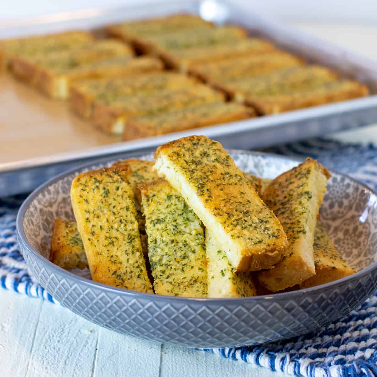 A serving bowl of garlic bread sticks.