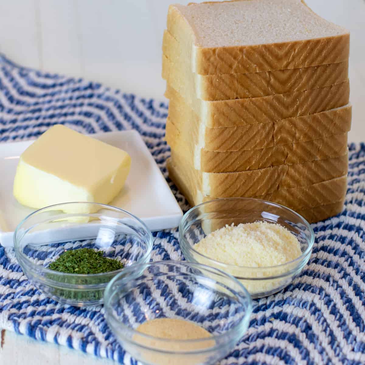 Ingredients for garlic bread arranged on a blue placemat.