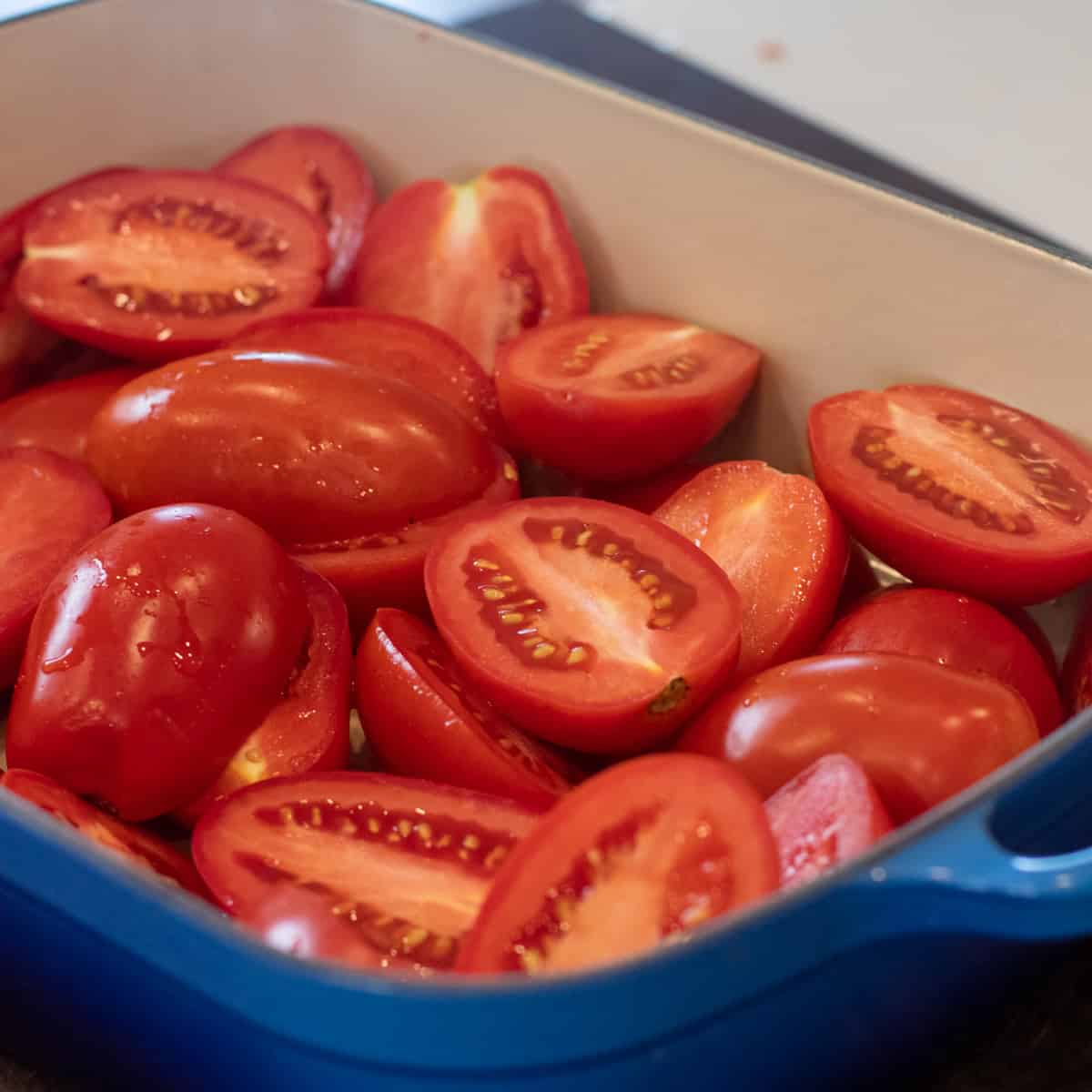 Halved plum tomatoes in a cast iron baking dish.