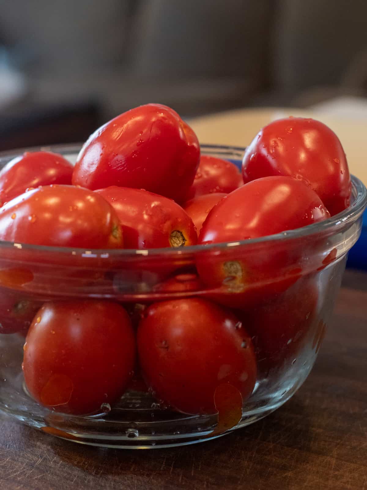 A glass bowl filled with plum tomatoes.
