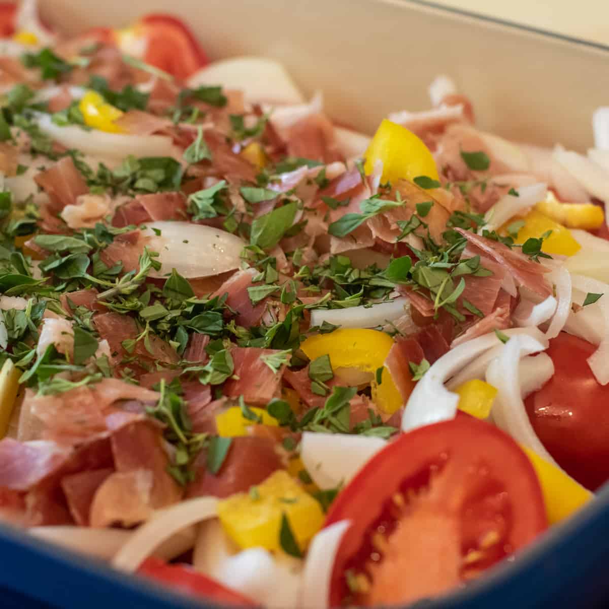 Chopped prosciutto and minced fresh oregano on a bed of tomatoes, onions and pepper.