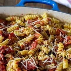 Roasted tomatoes and rotini pasta in a rectangular dish.