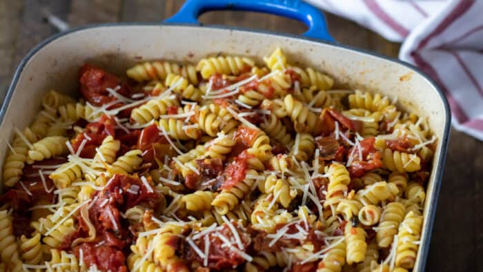 Roasted tomatoes and rotini pasta in a rectangular dish.
