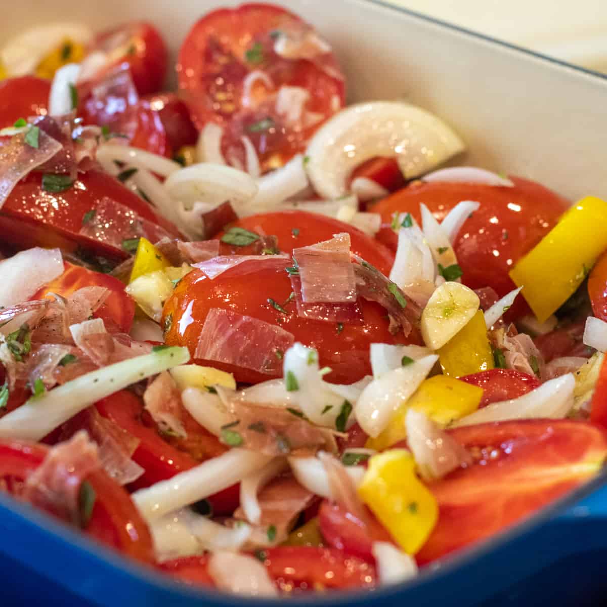 Cast iron baking dish filled with chopping ingredients and ready to go in the oven.