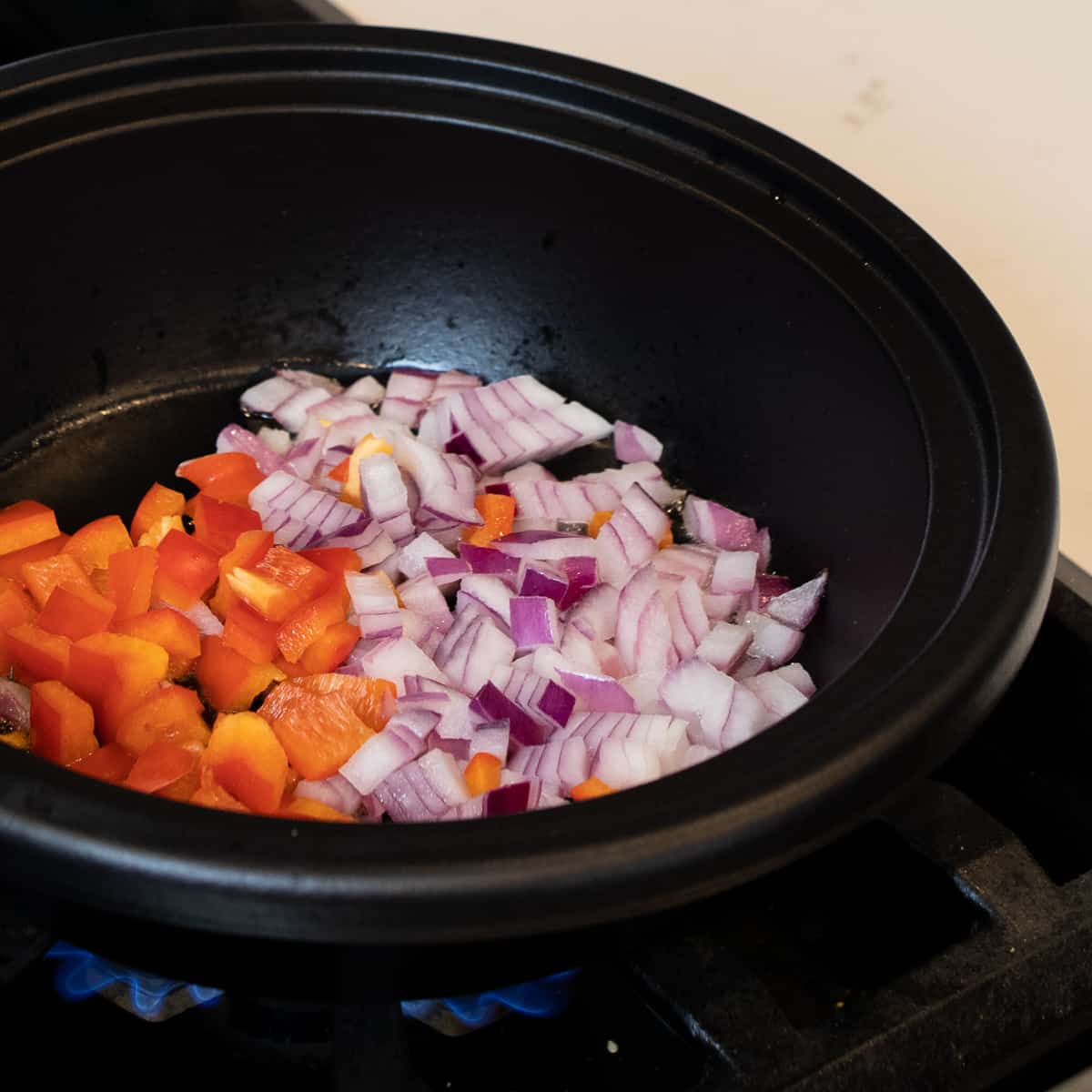 Diced red onions and red peppers in a cast iron skillet.