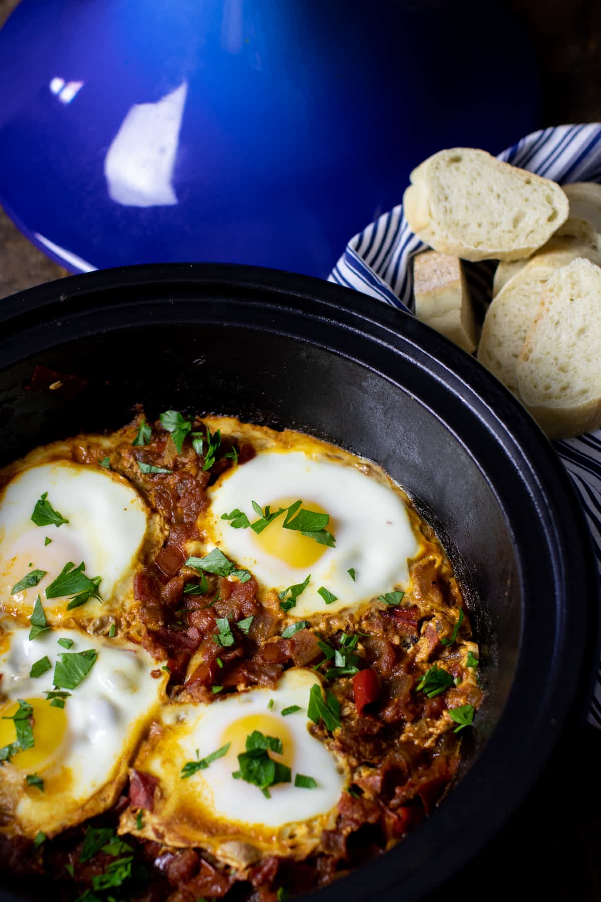 Eggs cooked in a cast iron tagine with a blue lid.