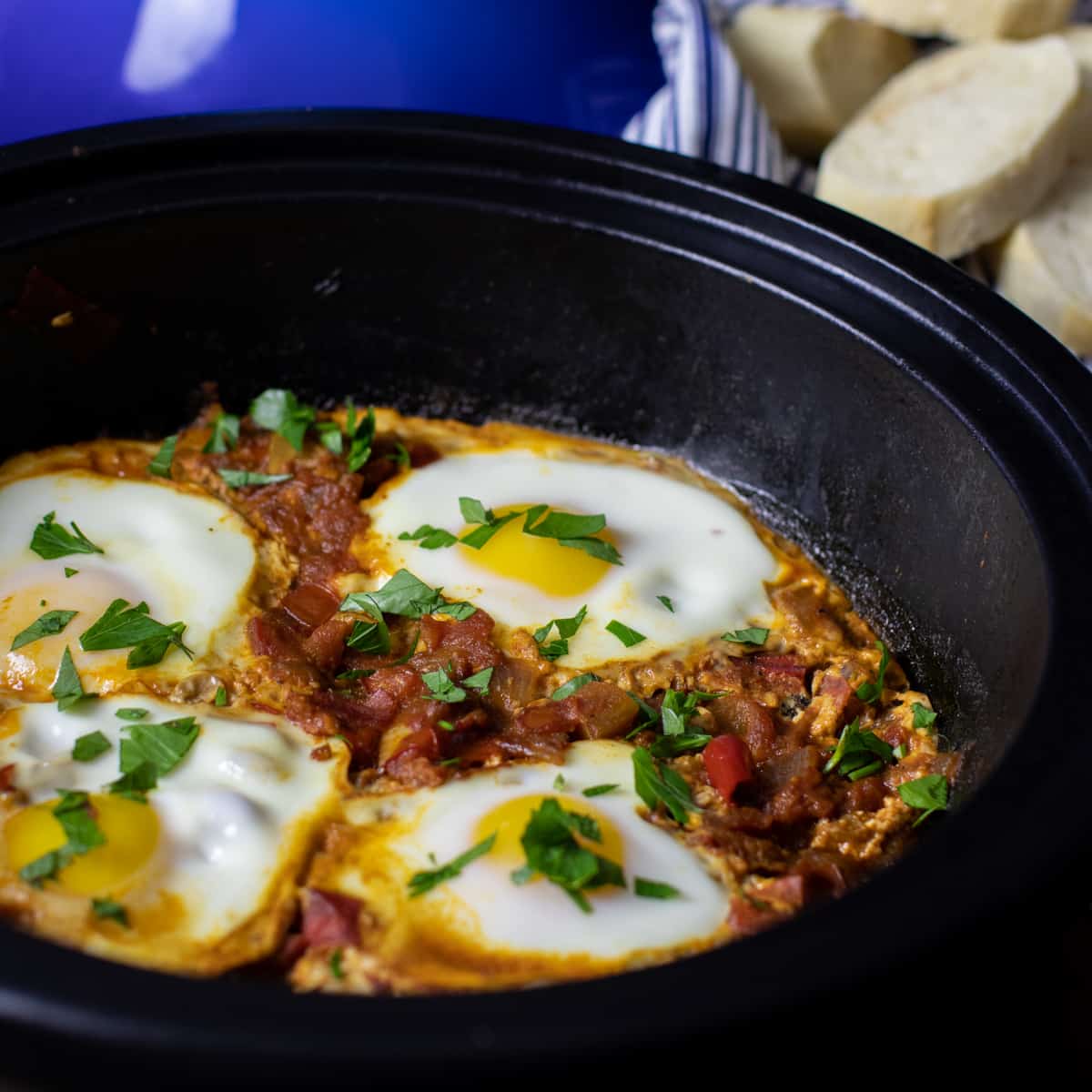 Shakshuka in a tagine with sliced bread.