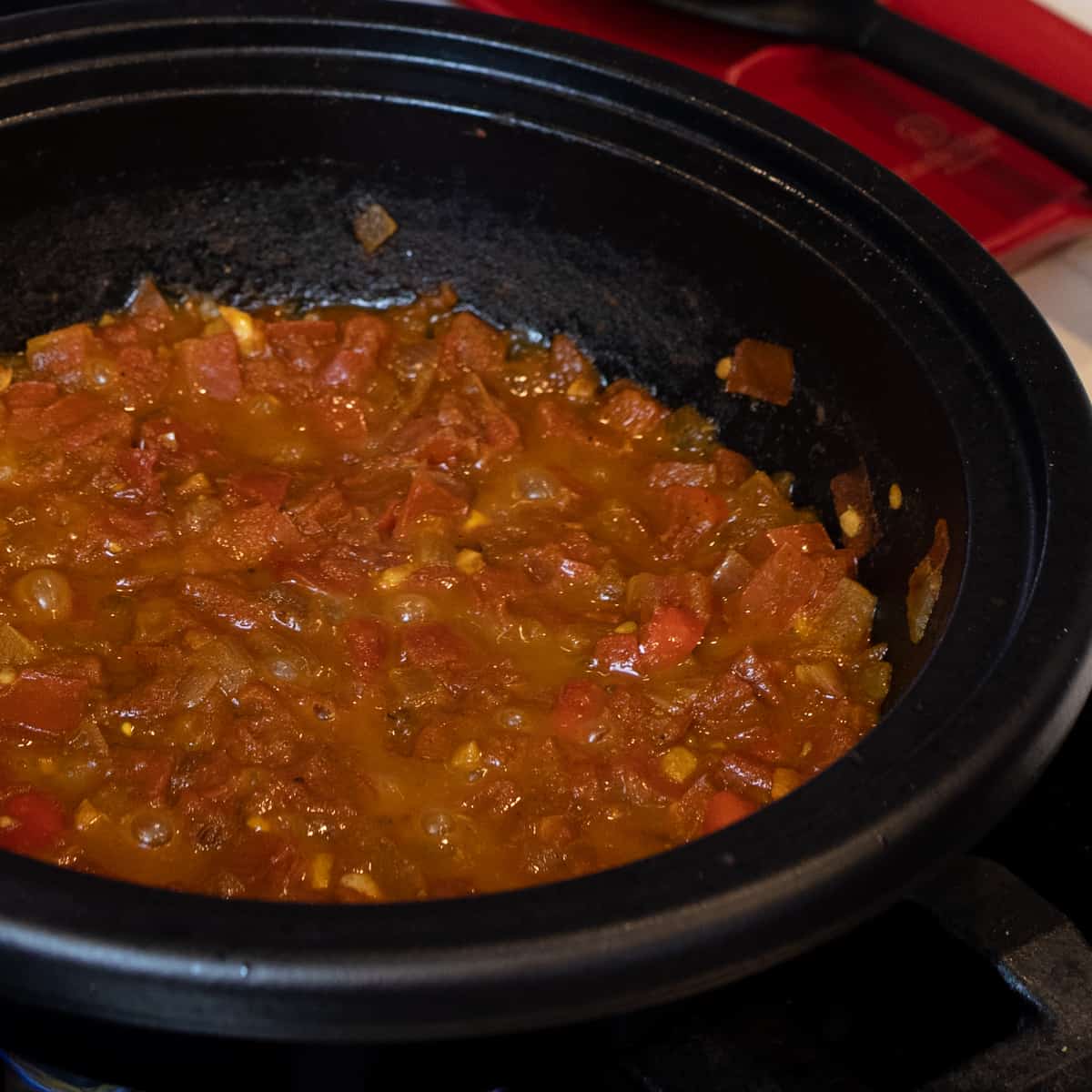 Tomatoes simmering in a cast iron skillet.