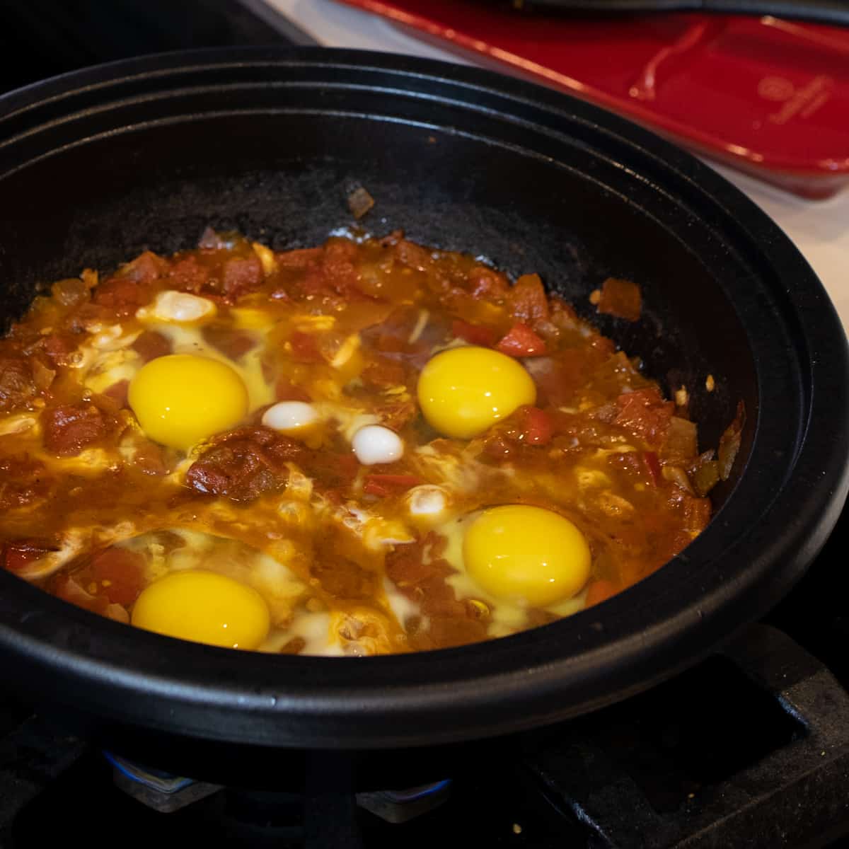 Four eggs freshly cracked on stewed tomatoes.
