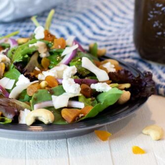 A plate of salad next to a jar of vinaigrette.