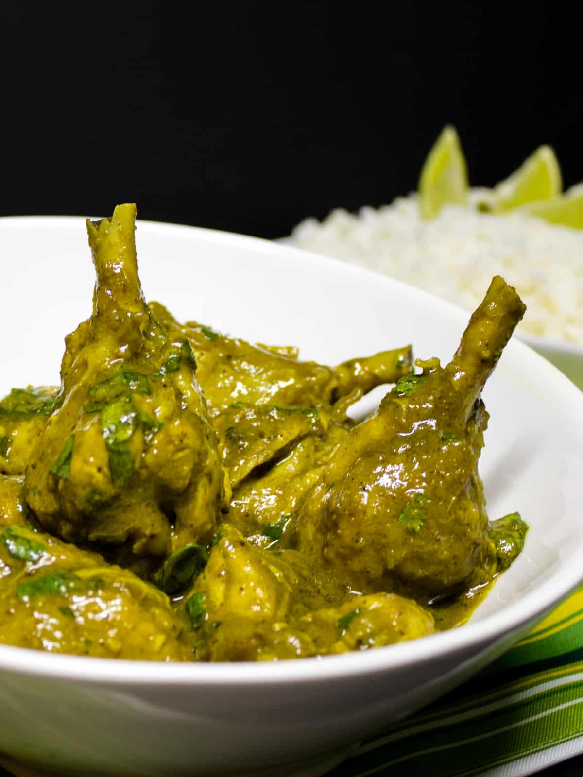 Chicken drumsticks with a curry sauce in a bowl.