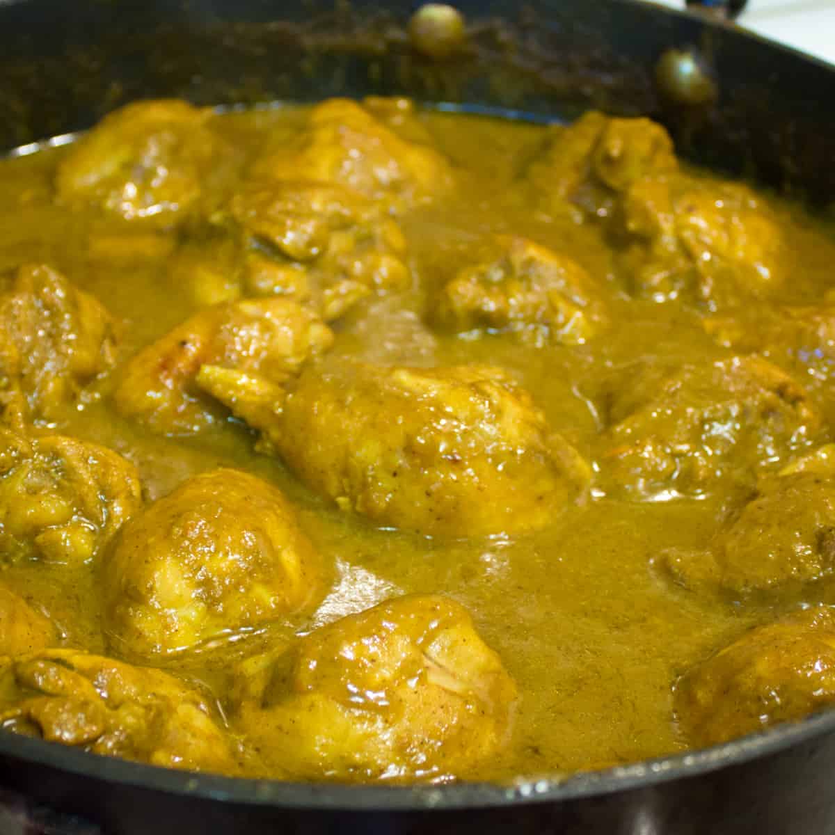 Curry chicken simmering in a skillet.