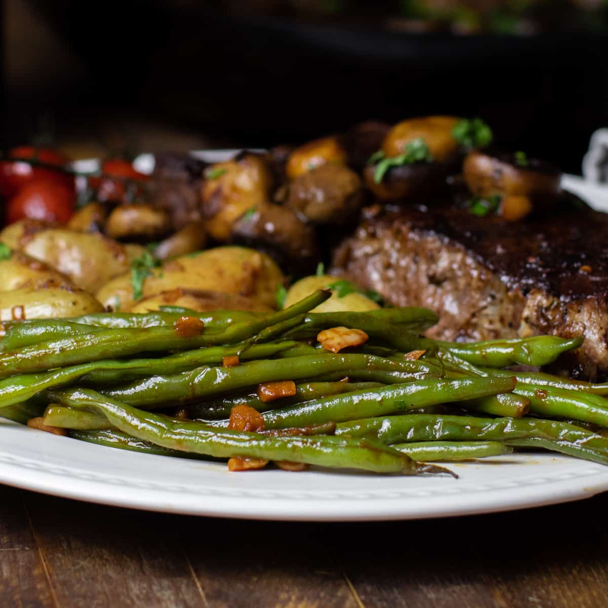 Green beans on a plate with steak and potatoes.
