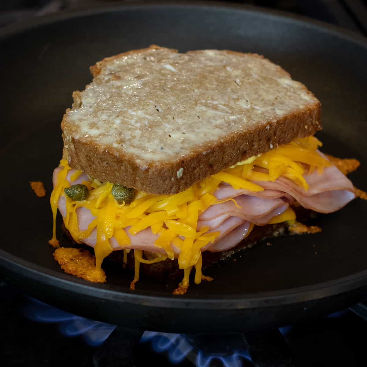 Grilled cheese starting to cook on a frying pan.