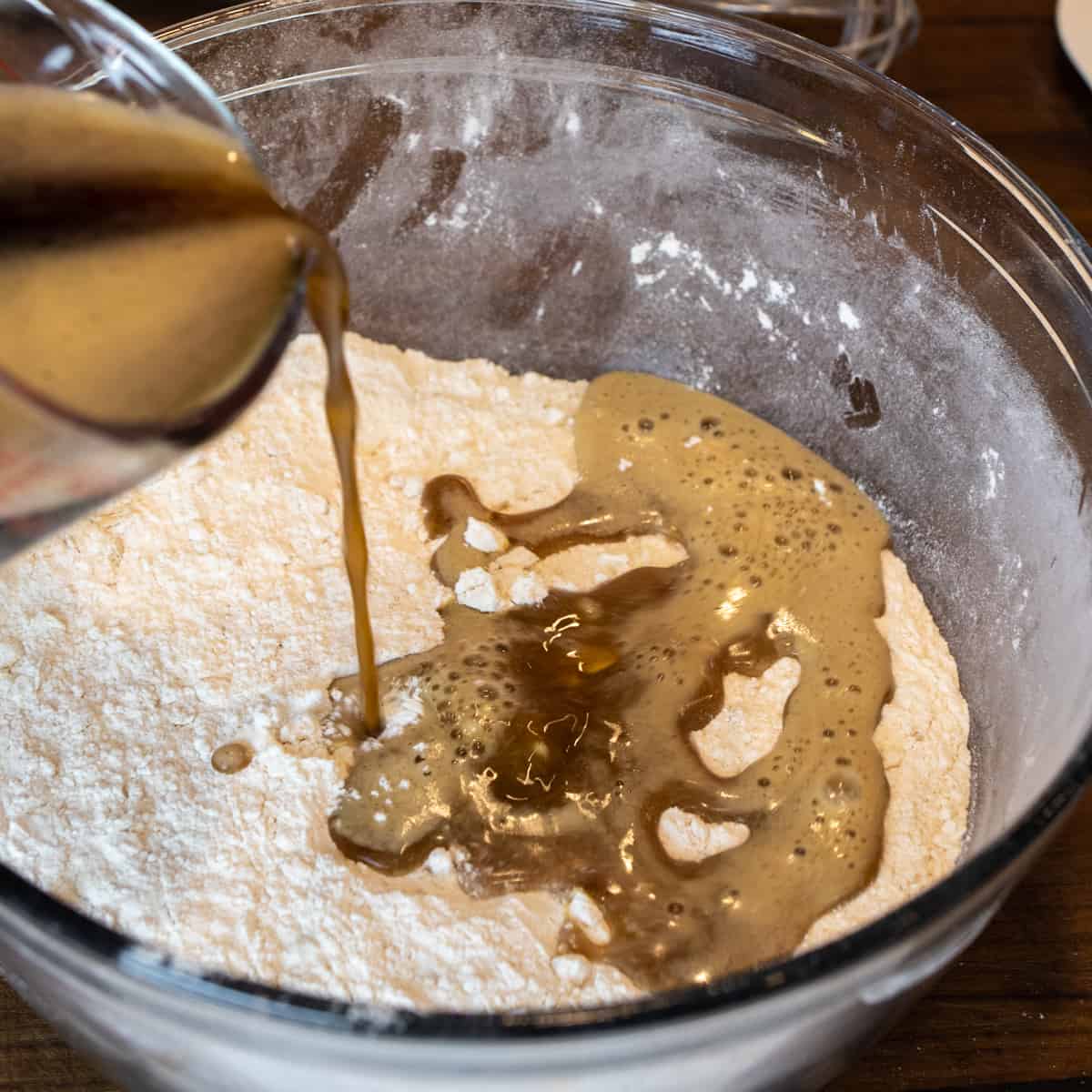 Pouring beer into a glass bowl with dry ingredients.