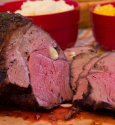 A sliced top sirloin beef roast on a cutting board.