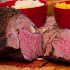 A sliced top sirloin beef roast on a cutting board.