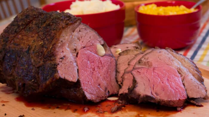 A sliced top sirloin beef roast on a cutting board.