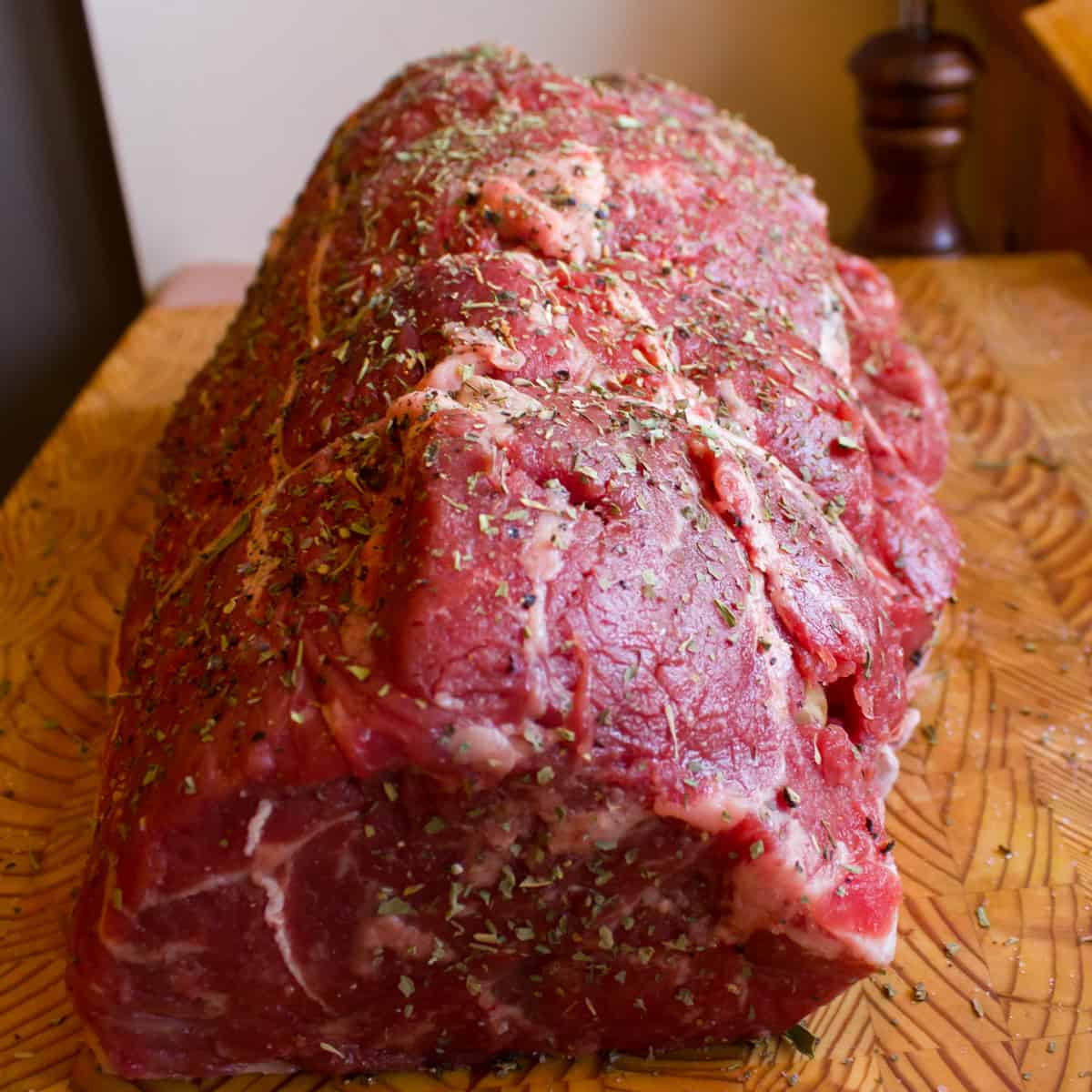 Seasoned raw beef roast resting on a cutting board.