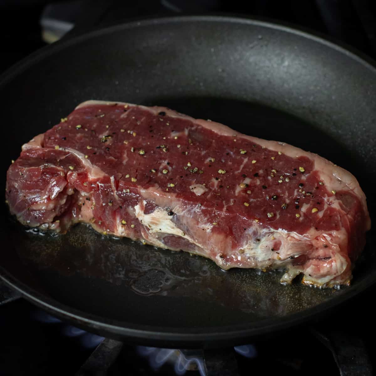 Raw steak placed on a hot frying pan.