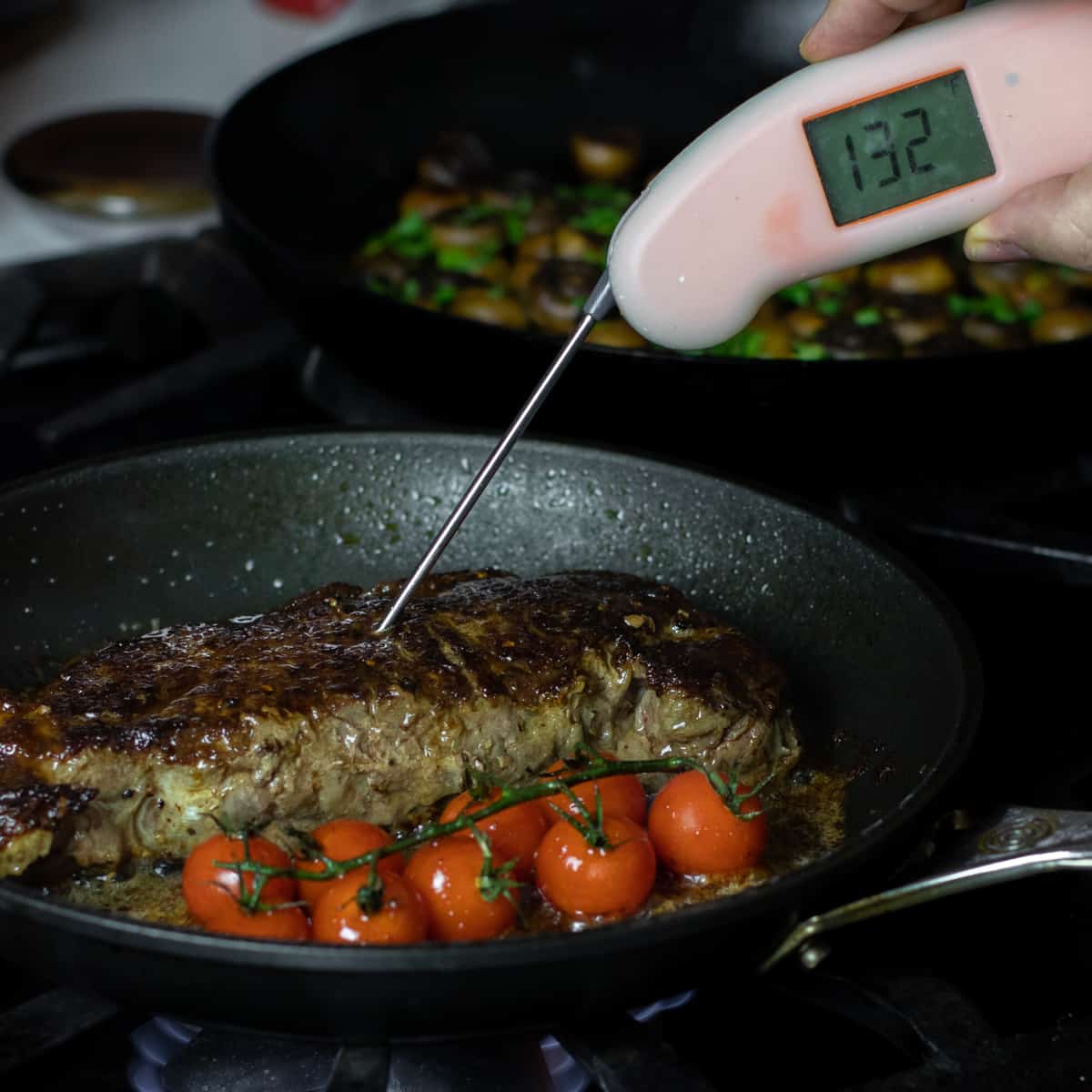 A digital thermometer stuck into a steak to check the temperature.