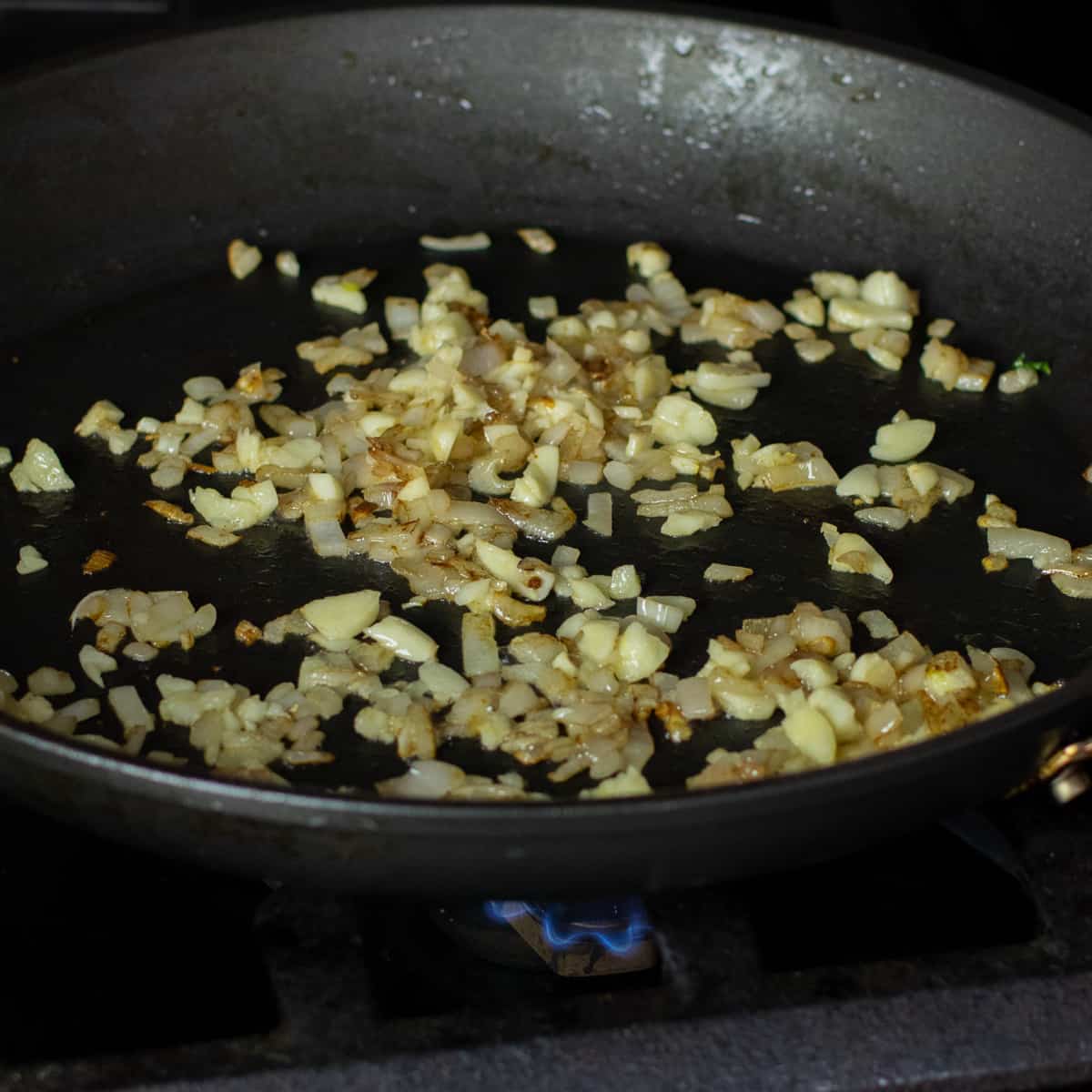 Minced shallot and garlic sautéing in a frying pan.