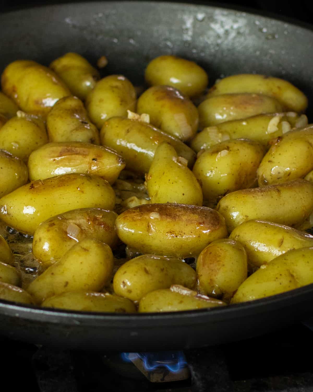 Boiled mini potatoes added to the frying pan with shallot and garlic.