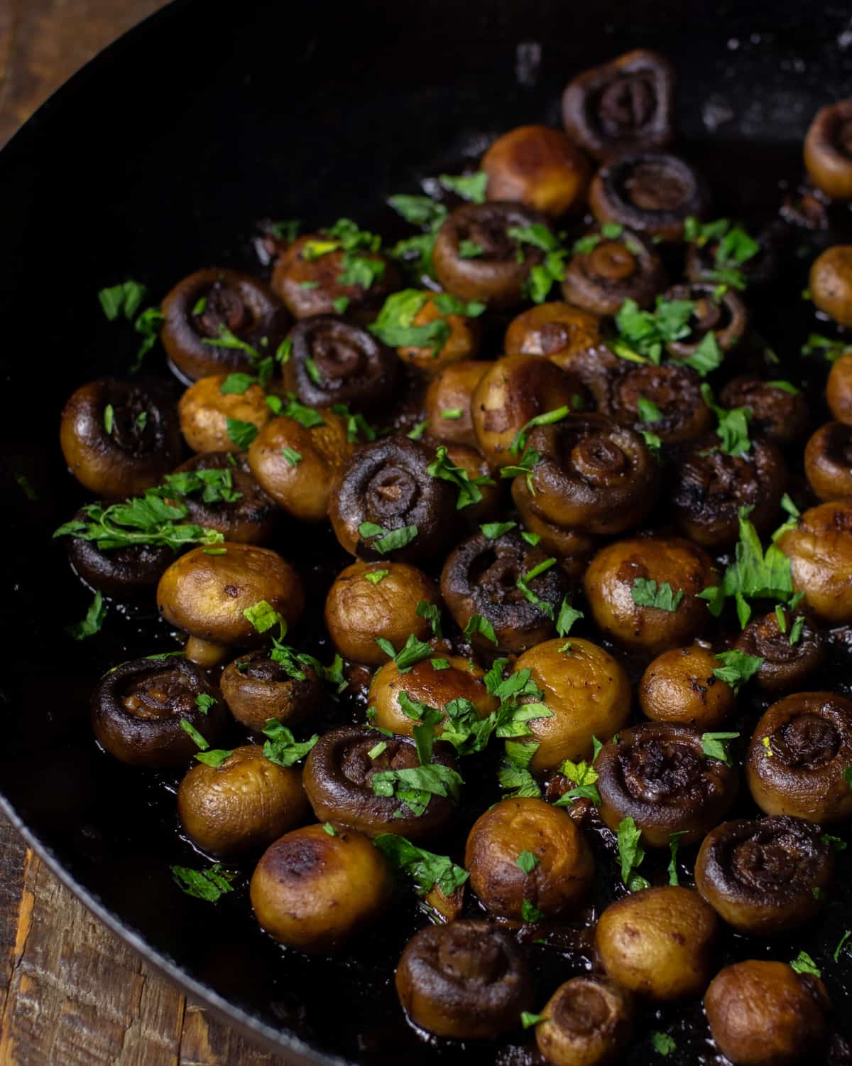 Overhead picture of cooked mushrooms sprinkled with parsley.