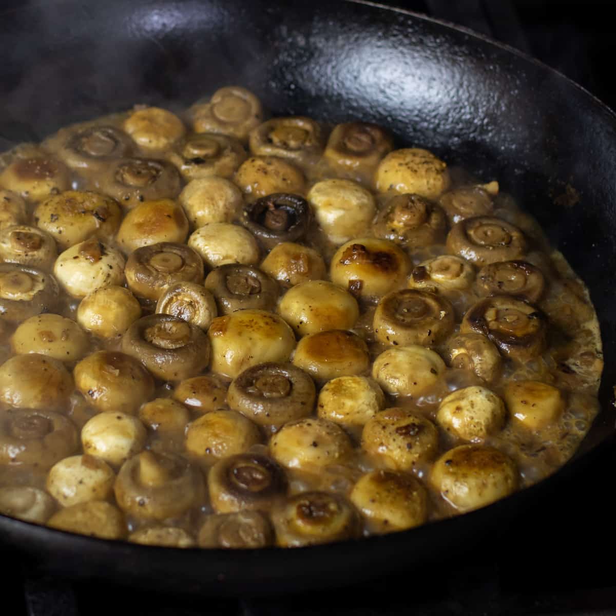 Mushrooms slowing cooking with broth.